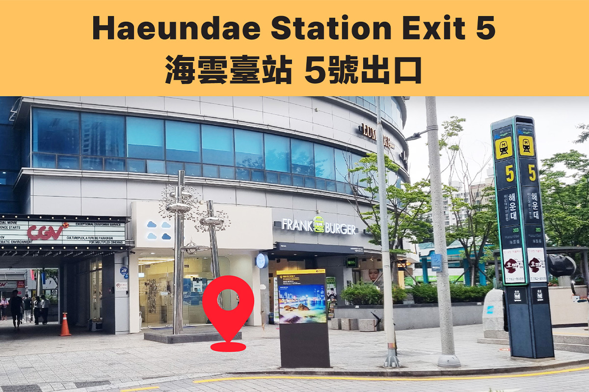 Entrance of Haeundae Station Exit 5 next to an advertisement board and metro signs in Busan, South Korea.